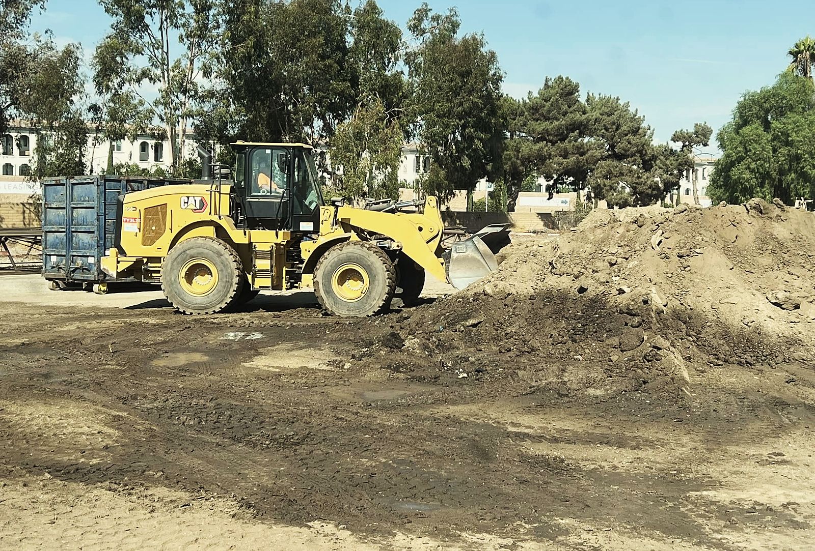 Yellow CAT wheel loader beside a large pile of export soil on an Anaheim job site
