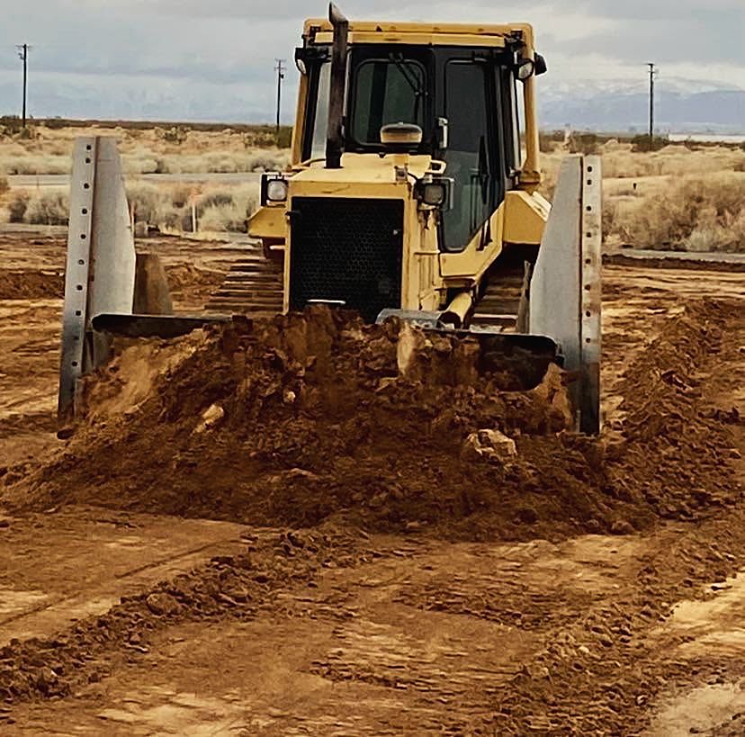 Track dozer pushing a pile of fill dirt across a desert site